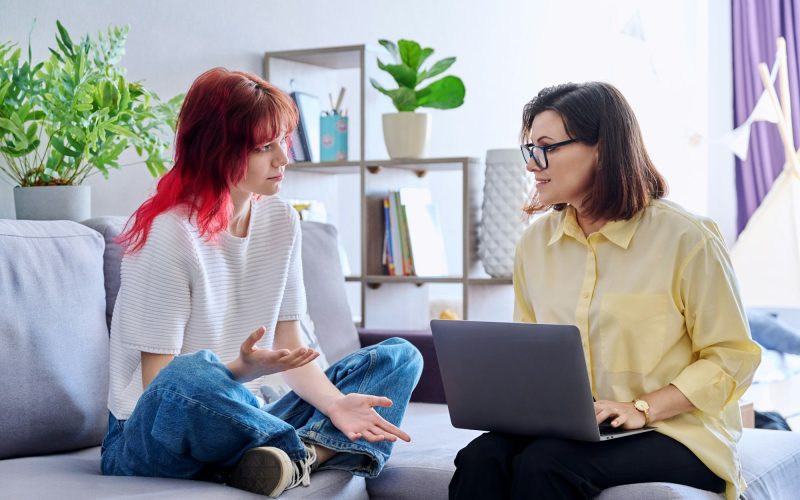 Therapy session for teenage girl, psychologist and patient together in office